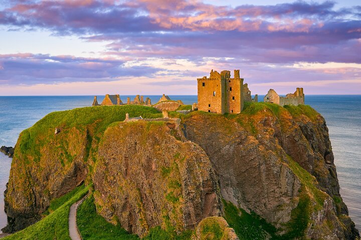 A rugged, green coastline with sea stacks and crashing waves in Scotland